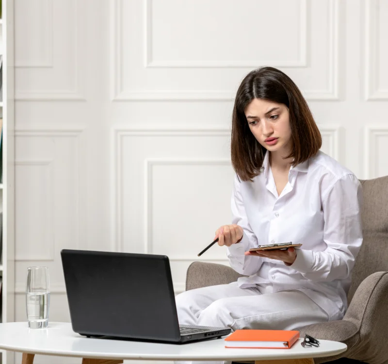 Therapist working on a laptop and tablet in her office while billing is handled by an outsourced team