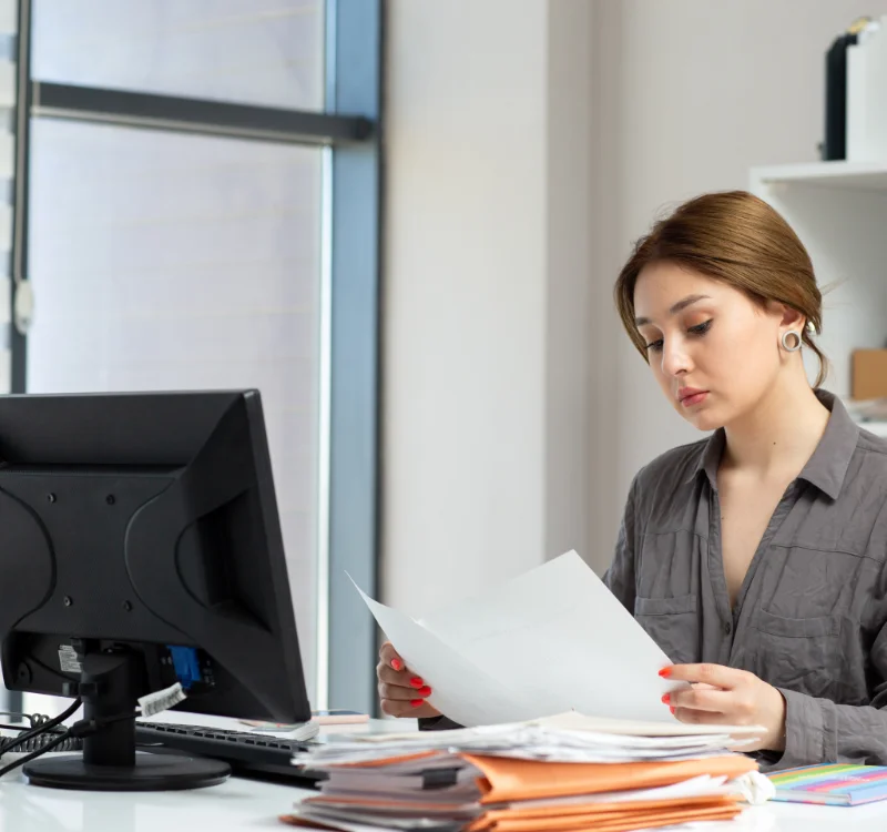 Practice manager reviewing insurance claim documents at her office desk